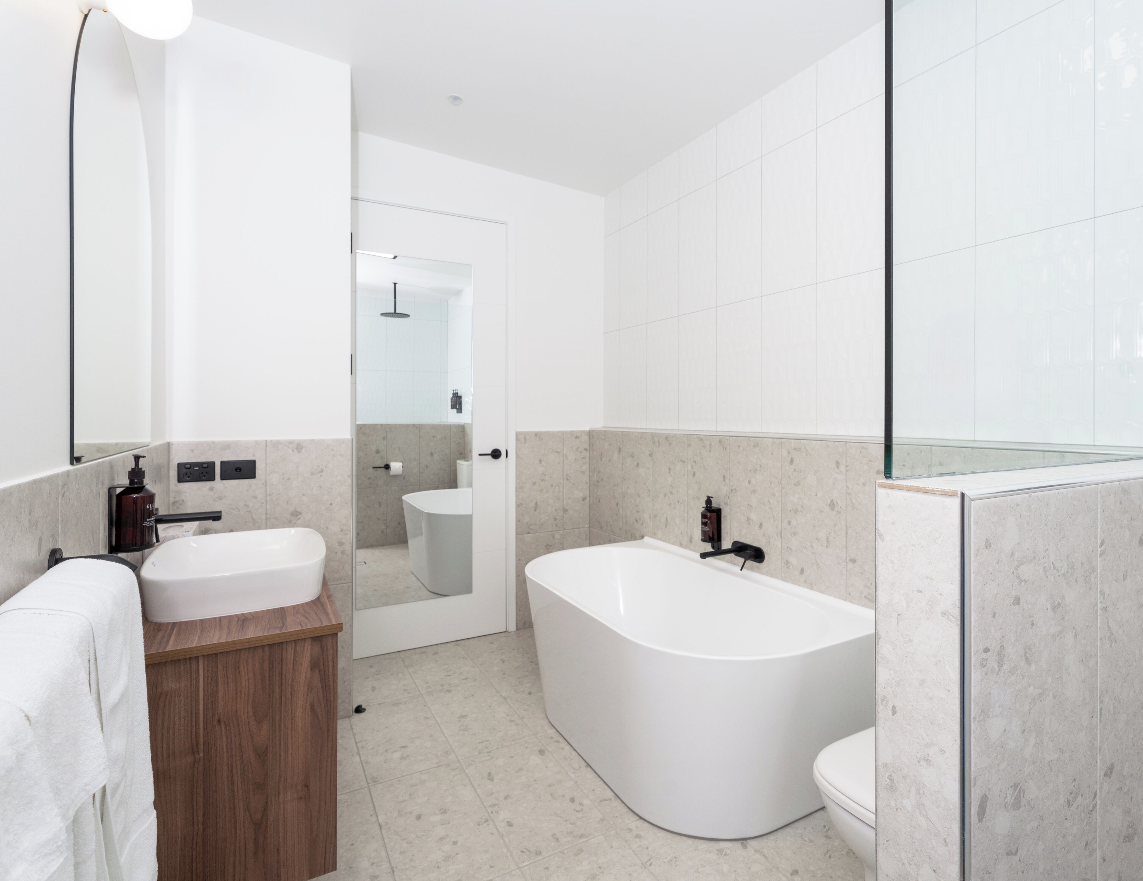 A modern bathroom with a freestanding bathtub, a vanity with a mirror, and a toilet.