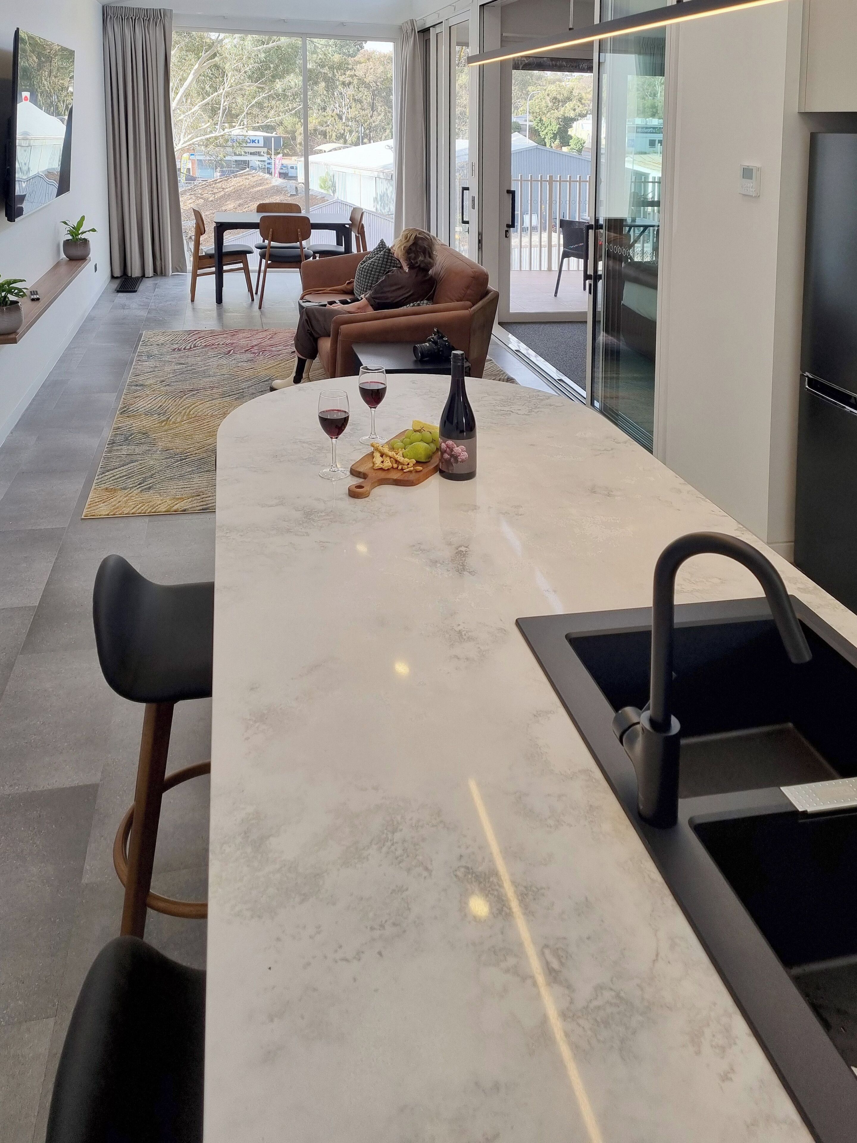 Une cuisine moderne dotée d’un plan de travail en marbre, d’un évier encastré et d’un coin repas avec une table et des chaises.
