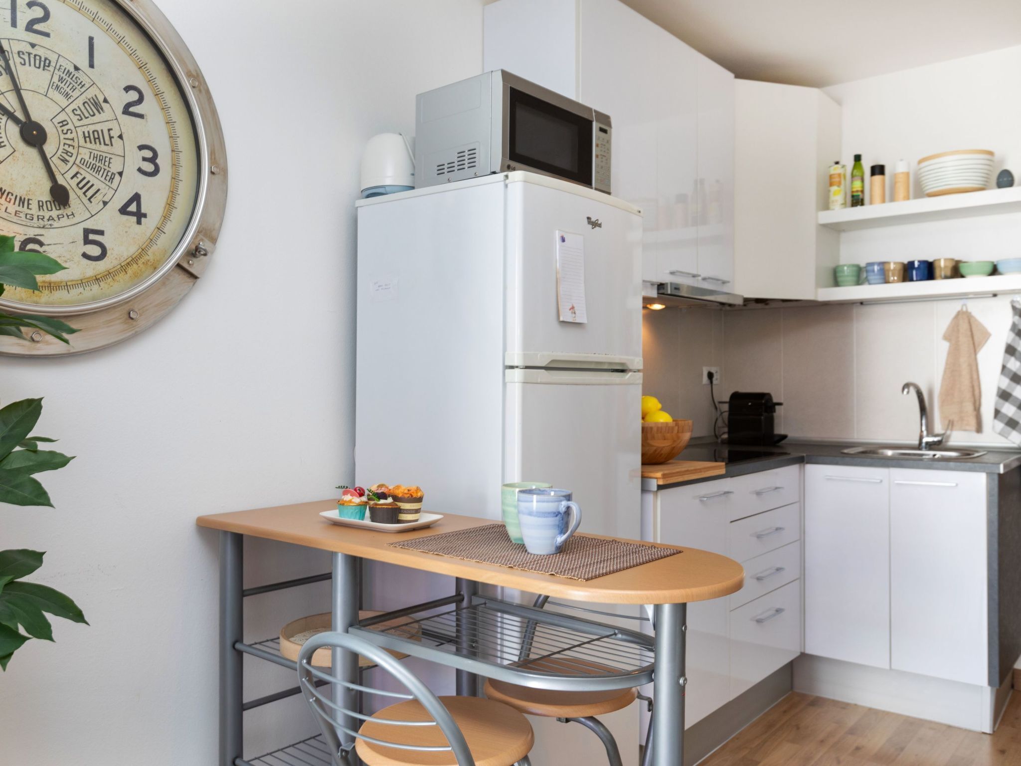 Une cuisine compacte équipée d’un four à micro-ondes, d’un réfrigérateur et d’une petite table à manger avec des chaises.