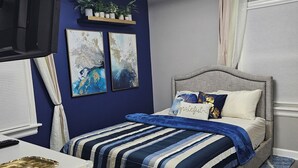 A bedroom with a bed, a desk, a TV, and a ceiling light. - Cozy 2BR Home in Delmar Loop (University City)