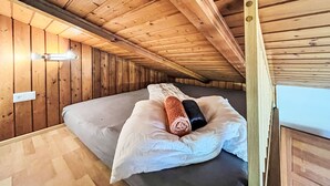 Ein Zimmer mit Holzwänden, einem Bett, einer Wandleuchte und einem Fenster.
