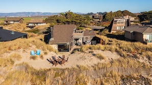 Una propiedad costera con casas modernas, un espacio de estar al aire libre techado y vistas a la playa y las montañas.
