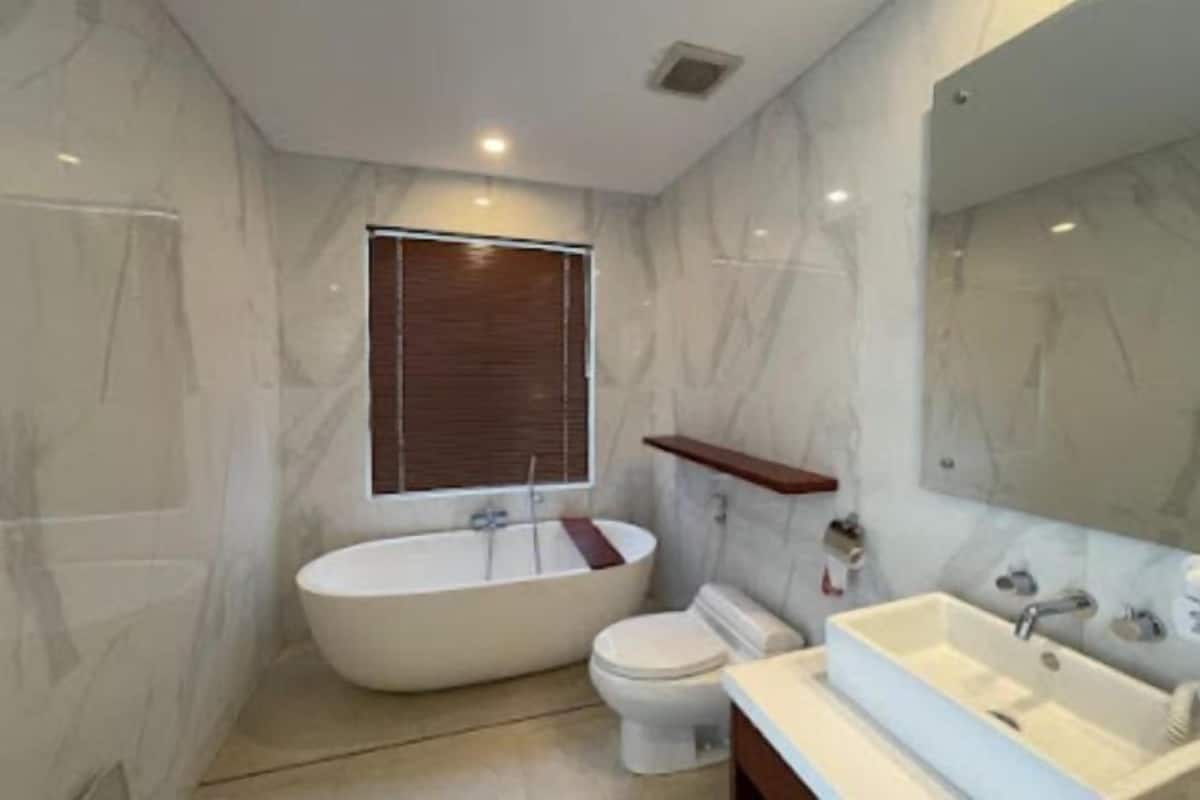A bathroom with a freestanding bathtub, a toilet, and a sink with a mirror above.