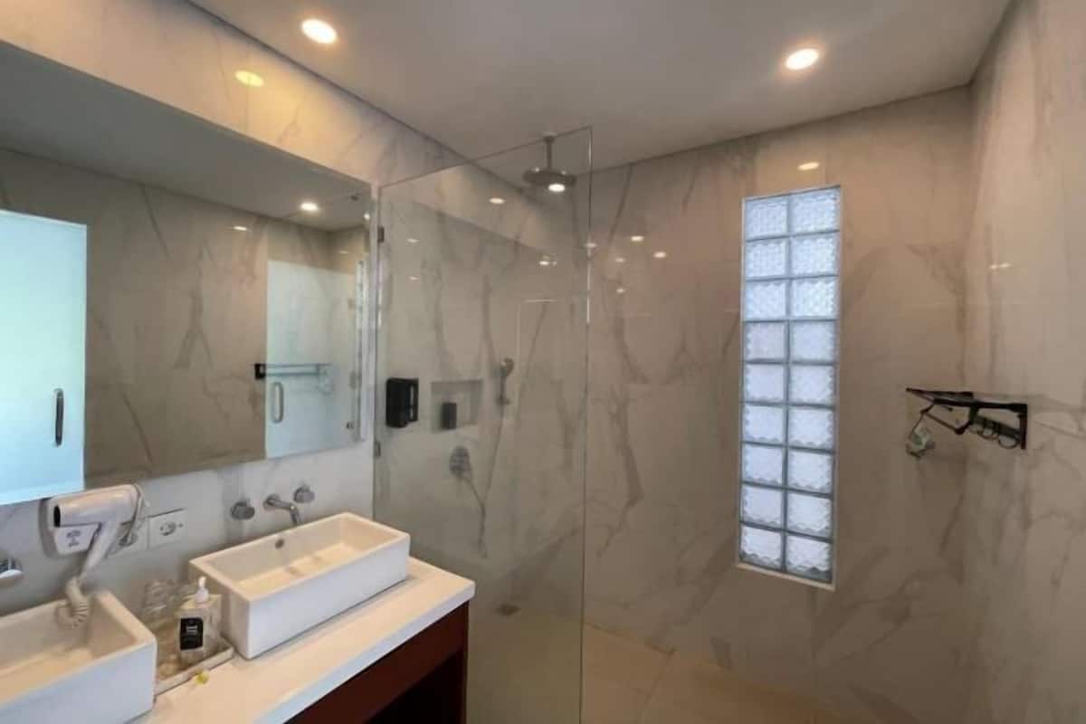 A modern bathroom with a glass-enclosed shower, a large mirror, and a vanity with a sink.