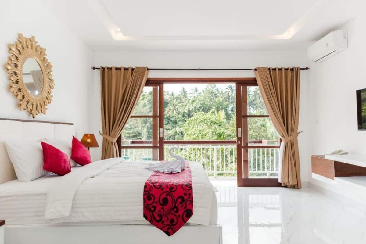 A hotel room with a large bed, a mirror, a TV, and a balcony with curtains.