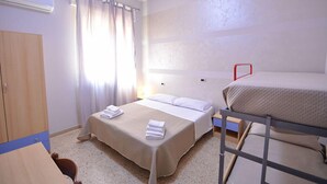 A room with two beds, a wooden wardrobe, a small table, and a window with curtains. - Hotel  Bella  Romagna  (Ravenna)