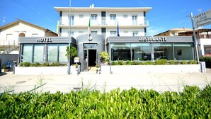 A hotel and restaurant with a modern facade, large glass windows, and a well-maintained garden area. - Hotel  Bella  Romagna  (Ravenna)