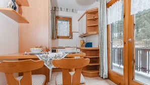 A cozy dining area with wooden furniture, a table set for two, and a window with a view of the outdoors.