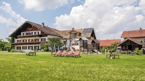 Il s’agit d’un bâtiment de style chalet traditionnel, doté d’un toit en pente, de balcons en bois et d’un petit espace extérieur aménagé avec des chaises rouges.