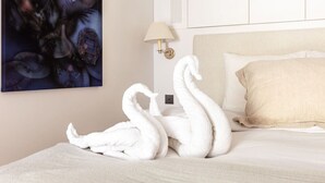 Een net opgemaakt bed met een beige kussen en een handdoek gevormd tot zwanen.