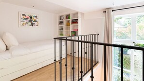 Een moderne woonkamer met een witte bank, een boekenkast en een zwarte balustrade.
