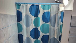 Un baño con cortina de ducha con un estampado circular azul y turquesa, un lavabo blanco y un tapete de piso azul.