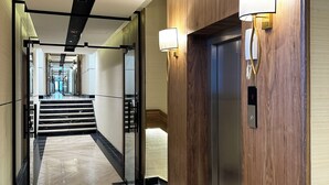 A modern hotel corridor with a marble floor, wooden paneling, and a staircase leading to an elevator. - Kease Yasmin 4-13 Ramz Terrace AG74 (Riyadh)
