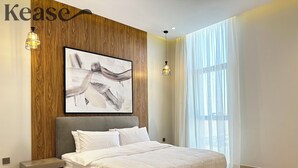 A modern bedroom with a large bed, a wooden accent wall, and a large abstract painting. - Kease Yasmin 4-13 Ramz Terrace AG74 (Riyadh)