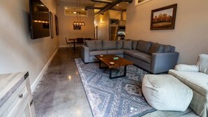 Ein modernes Wohnzimmer mit einem Ecksofa, einem Couchtisch und einem gemusterten Teppich.