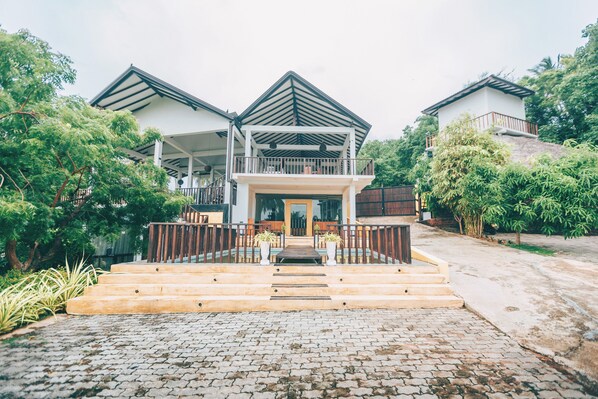 A two-story house with a balcony, a front porch, and a staircase leading to the entrance.
