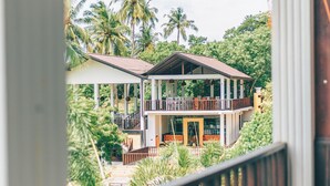 A two-story building with a balcony, surrounded by lush greenery and palm trees. - Samudra Beach Resort (Rekawa)