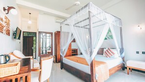 A bedroom with a four-poster bed, a desk with a chair, and a bedside table. - Samudra Beach Resort (Rekawa)