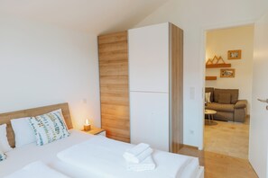 Ein Hotelzimmer mit Bett, Nachttisch, Holzwand und Blick in den Wohnbereich.