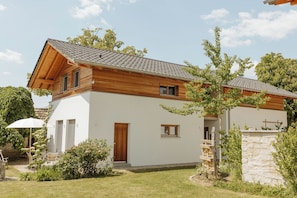 Ein modernes, zweistöckiges Haus mit Satteldach, Holzfassade und einer Steinwand.