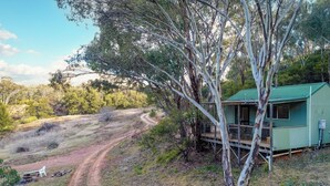 A small, single-story building with a green roof, surrounded by trees and a dirt path. - Tanwarra Lodge (Sofala)