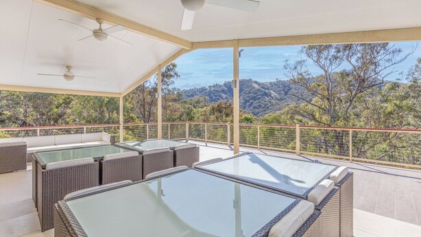 A covered outdoor area with a pool table, seating, and a scenic view of trees and hills. - Tanwarra Lodge (Sofala)