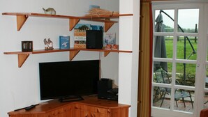 Een hoekzaak met een houten kast, televisie en planken.