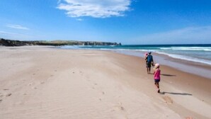 Ein weiter, sandiger Strand bei klarem Himmel.