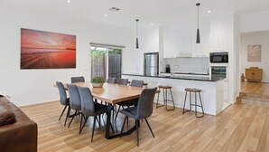 Eine moderne Küche mit weißen Schränken, einer zentralen Kochinsel und einem Essbereich mit Holztisch und Stühlen.