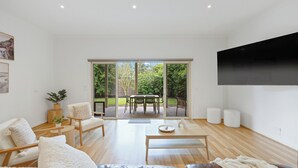 Ein modernes Wohnzimmer mit einer Couch, einem Couchtisch und einem an der Wand montierten Fernseher.