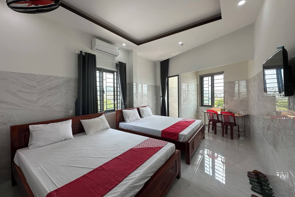 A hotel room with two beds, a desk, and a chair.