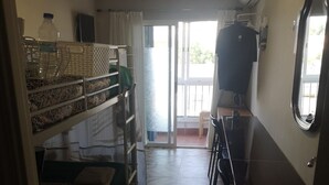 A compact room with bunk beds, a dining table, and a window.