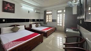 A hotel room with two beds, a desk, a chair, a TV, and a window with curtains.
