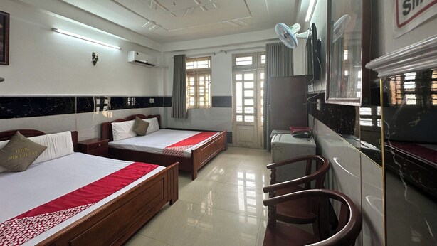 A hotel room with two beds, a desk, a chair, a TV, and a window with curtains.