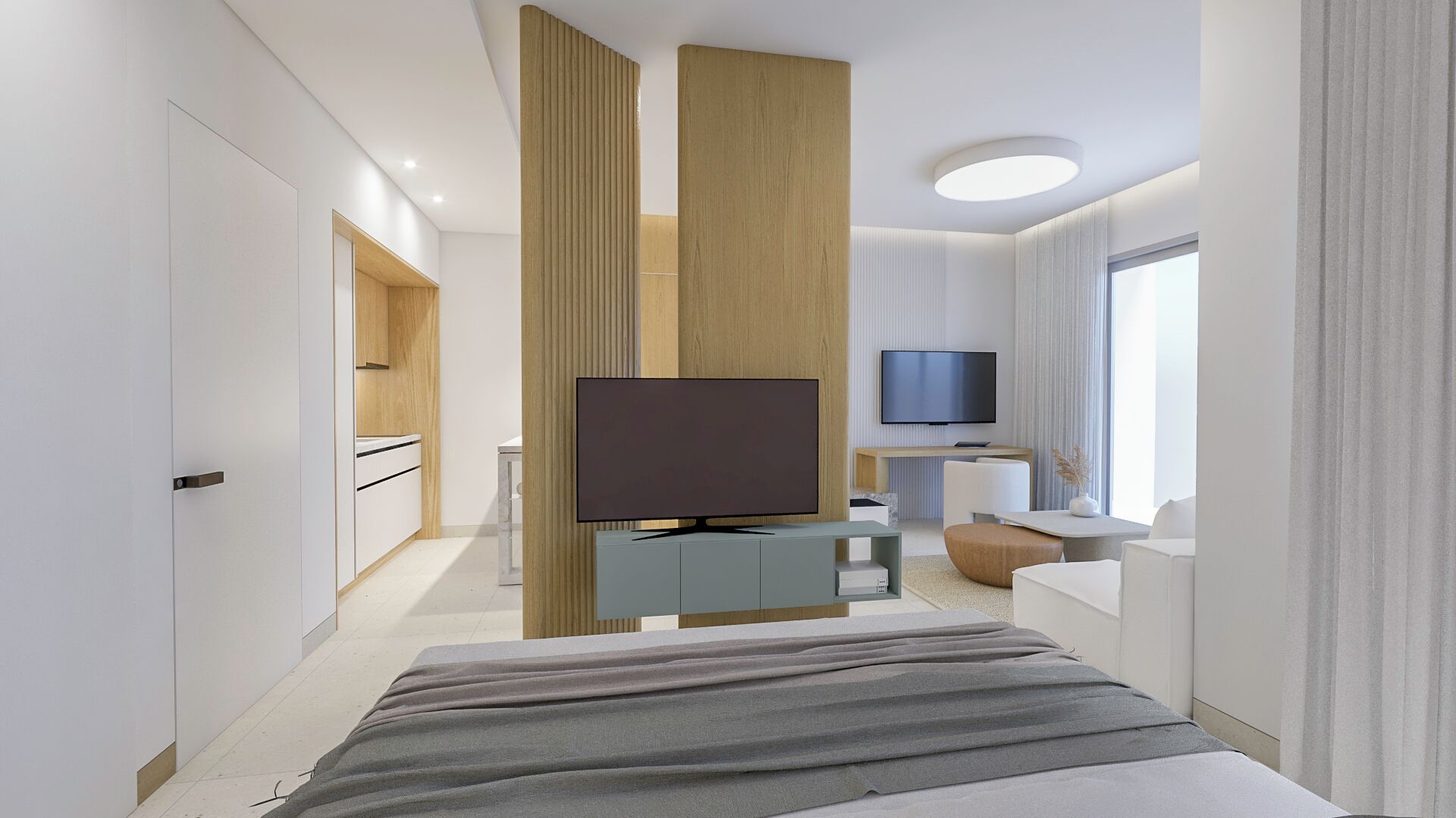 Quarto de hotel moderno com uma cama grande, televisão de tela plana, uma escrivaninha pequena e um espaço de estar com sofá e banquinho.