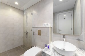 A modern bathroom with a glass-enclosed shower, a white sink, and a marble countertop.
