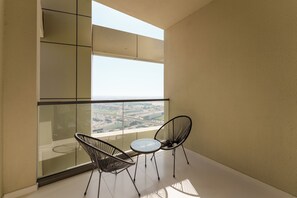 A balcony with two chairs and a table, offering a view of a cityscape.