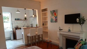 A modern living room with a fireplace, a television, and a blue armchair. - Amazonia Rouen Centre by Myfrenchpat (Rouen)