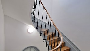 A spiral staircase with wooden steps and black balusters, leading to a landing with a window. - Amazonia Rouen Centre by Myfrenchpat (Rouen)