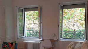 A bedroom with a bed, two windows, a chair, a desk, and a radiator. - Amazonia Rouen Centre by Myfrenchpat (Rouen)