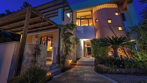 Une maison moderne dotée d’une façade incurvée, d’un porche abrité et d’une entrée bien éclairée.