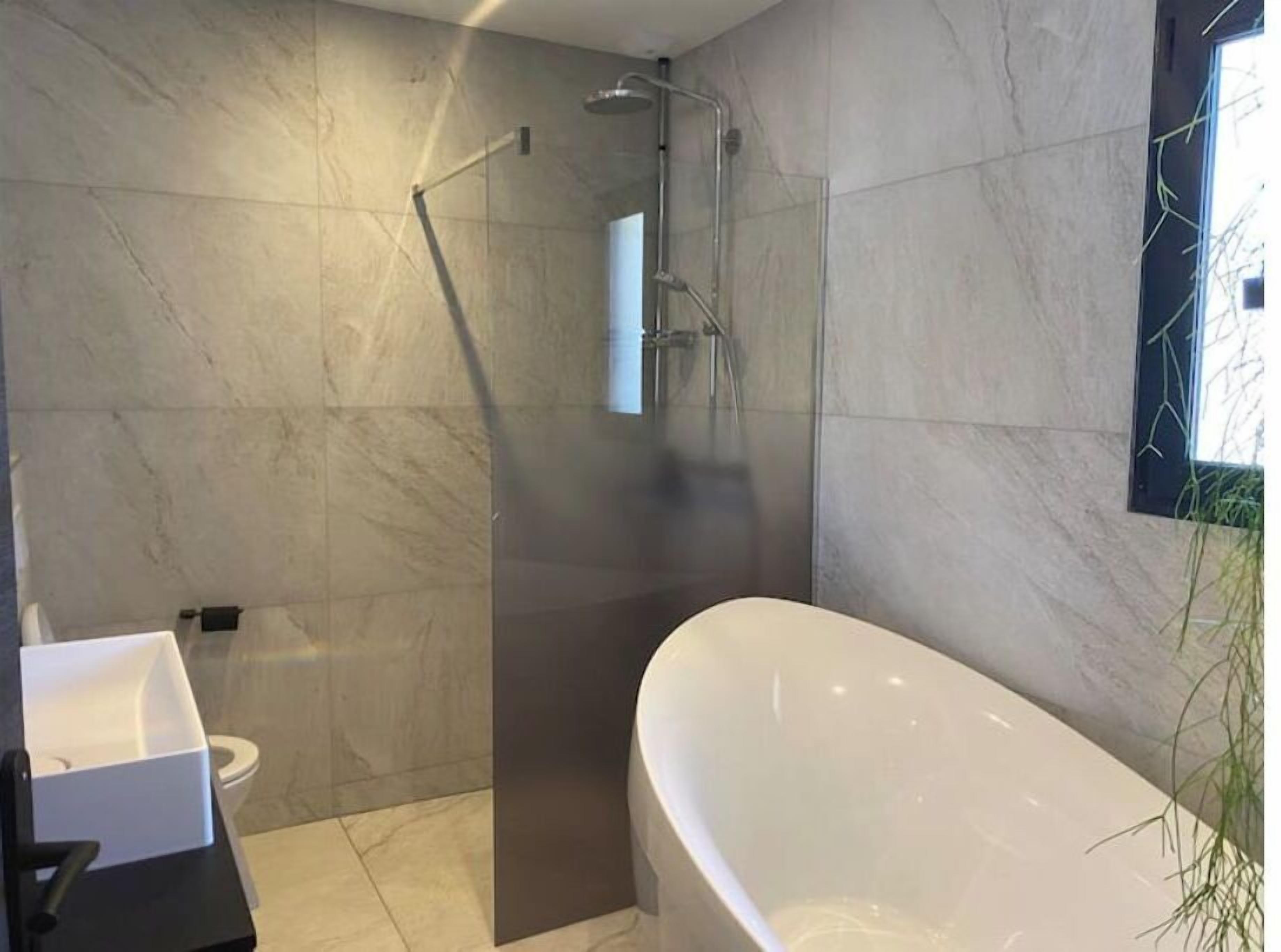 A modern bathroom with a freestanding bathtub, a glass-enclosed shower, and a toilet.