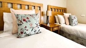Une chambre d’hôtel avec deux lits, une table de chevet avec une lampe et un tableau encadré au mur.