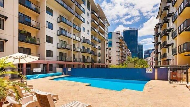 Une cour avec une piscine, des immeubles à plusieurs étages et des espaces de détente en plein air.
