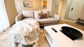 Un salon comprenant un canapé, un pouf et une table basse avec une télécommande.