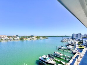 A marina with boats docked, a clear blue sky, and buildings in the background. - Sandpipers Cove 602 - Waterfront Penthouse (Clearwater Beach)