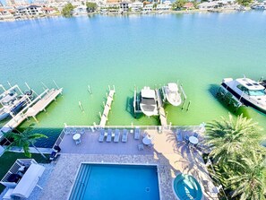 A marina with boats docked, a swimming pool, and a deck with lounge chairs. - Sandpipers Cove 602 - Waterfront Penthouse (Clearwater Beach)