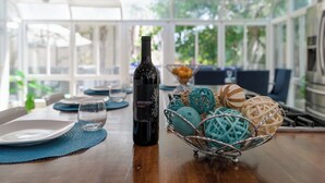Una mesa de comedor con una botella de vino, platos y una cesta decorativa.
