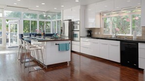 Una cocina moderna con armarios blancos, electrodomésticos de acero inoxidable y una isla grande con taburetes de bar.