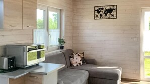 Kompakti olohuone, jossa on pieni keittiönurkkaus, harmaa sohva ja maailmankartta seinällä.